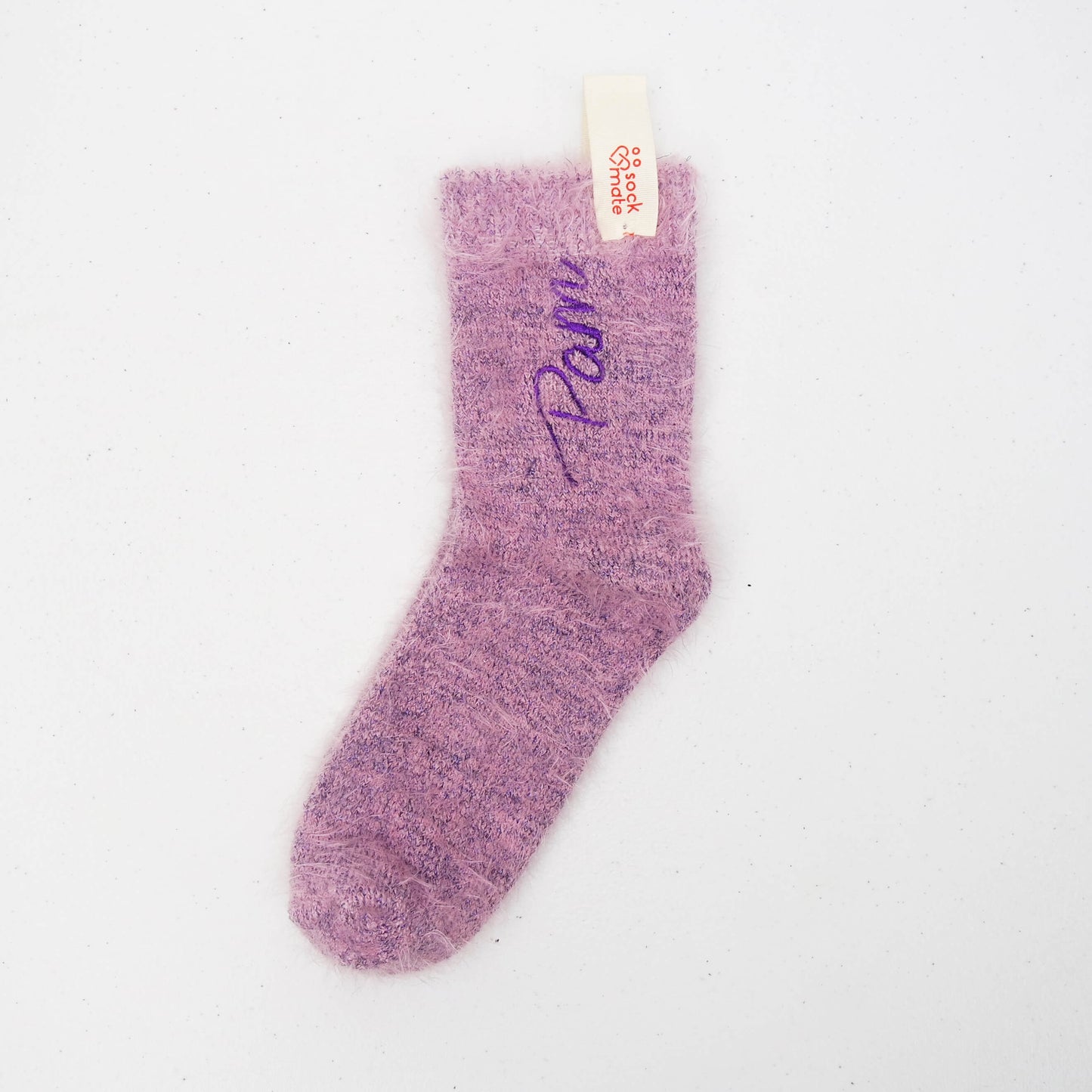 Soft lilac fuzzy sock with “Pam” embroidered in purple on one side, displayed flat with a Sockmate tag on white background.