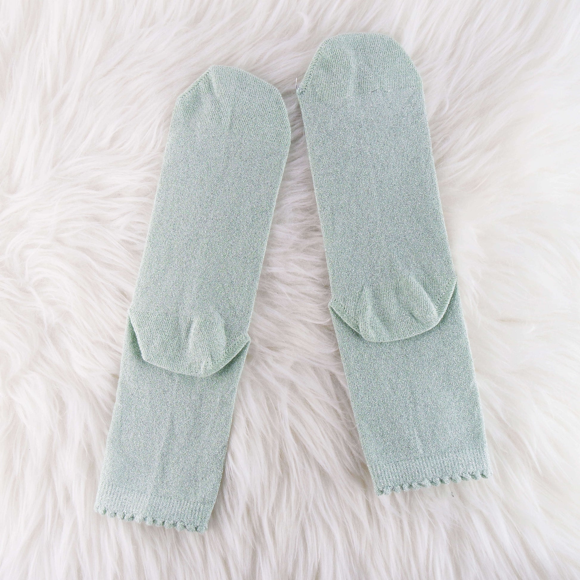 sage glitter socks, providing a stylish and shimmery accessory to enhance the overall look of any outfit.