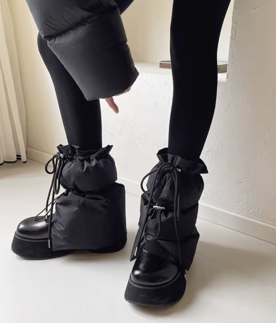 Gray quilted puff boot covers with drawstring ties, worn over sneakers and paired with black leggings.