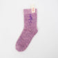 Soft lilac fuzzy sock with “Pam” embroidered in purple on one side, displayed flat with a Sockmate tag on white background.