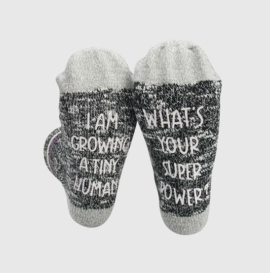 socks with a playful message, acknowledging the challenges of pregnancy with the phrase 'Sorry I just can't today, I am growing a tiny human.
