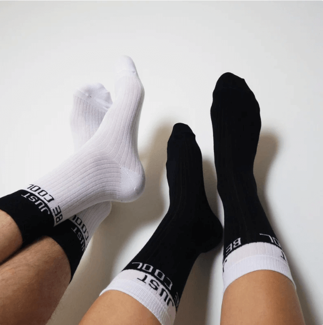 showcasing couple's socks with the phrase 'Just Be Cool,' expressing a light-hearted and carefree vibe."