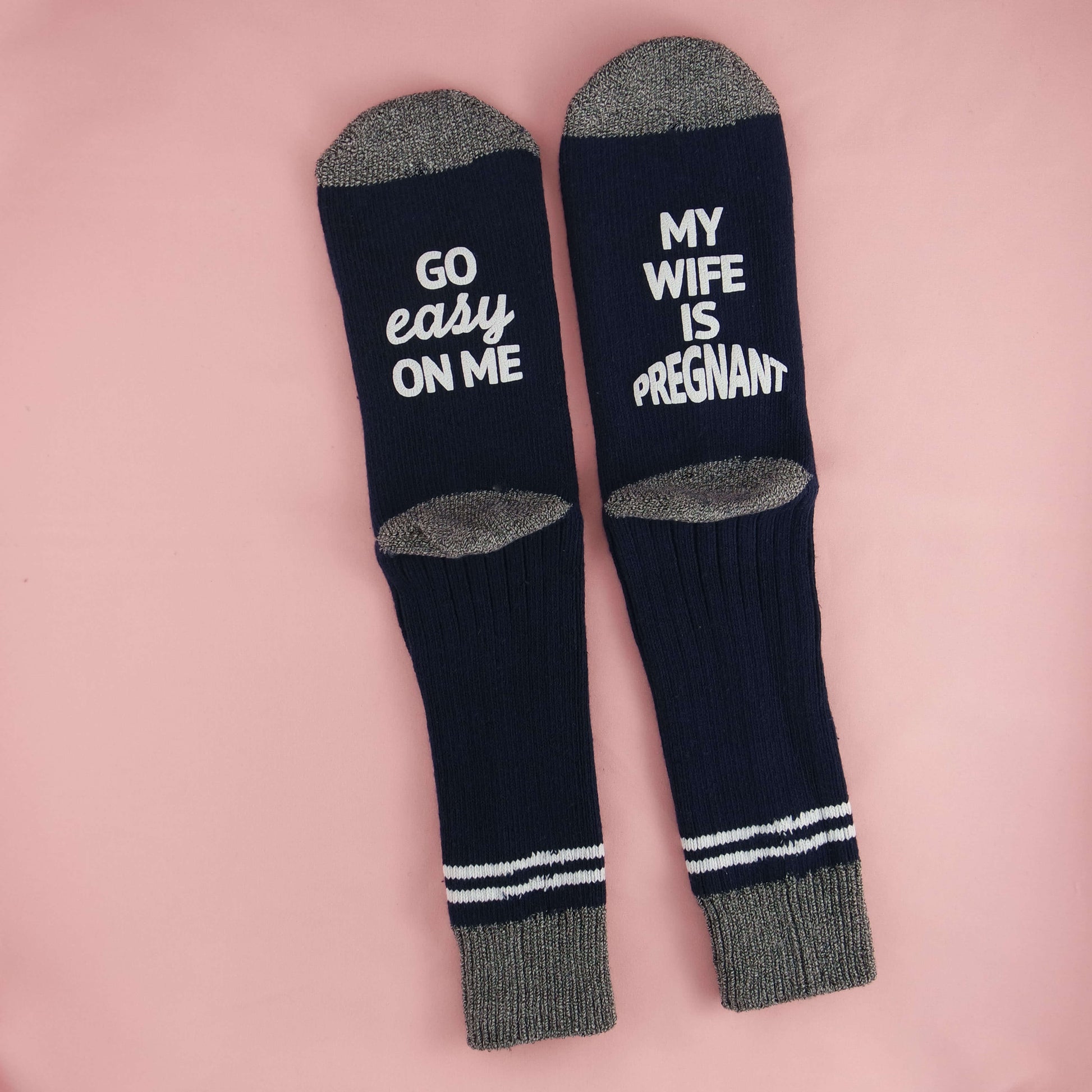 Socks conveying a playful and supportive message for partners of pregnant women, with the phrases 'GO EASY ON ME' and 'MY WIFE IS PREGNANT,' encouraging empathy and patience.