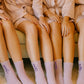 Bride and bridesmaids wearing personalized lilac embroidered socks with names Allison, Jessica, and Olivia, sitting together before the wedding.