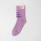 Single fuzzy lilac sock with purple embroidered text “to baby mama,” displayed flat with Sockmate brand tag attached at the cuff.
