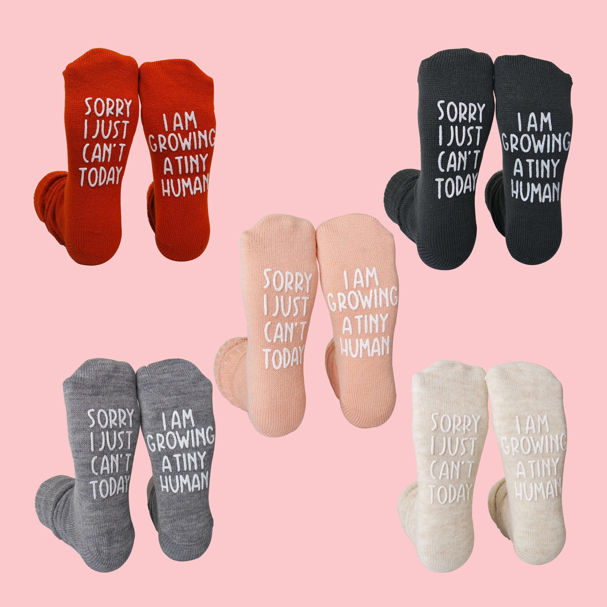 Set of baby socks with humorous text on a pink background